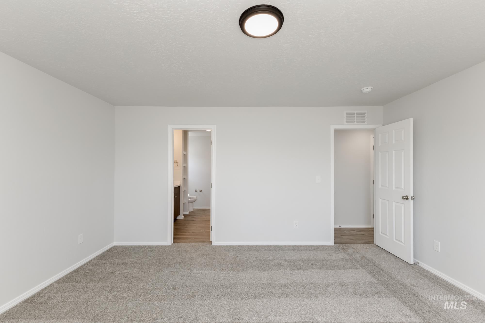 Unfurnished bedroom featuring light carpet and connected bathroom