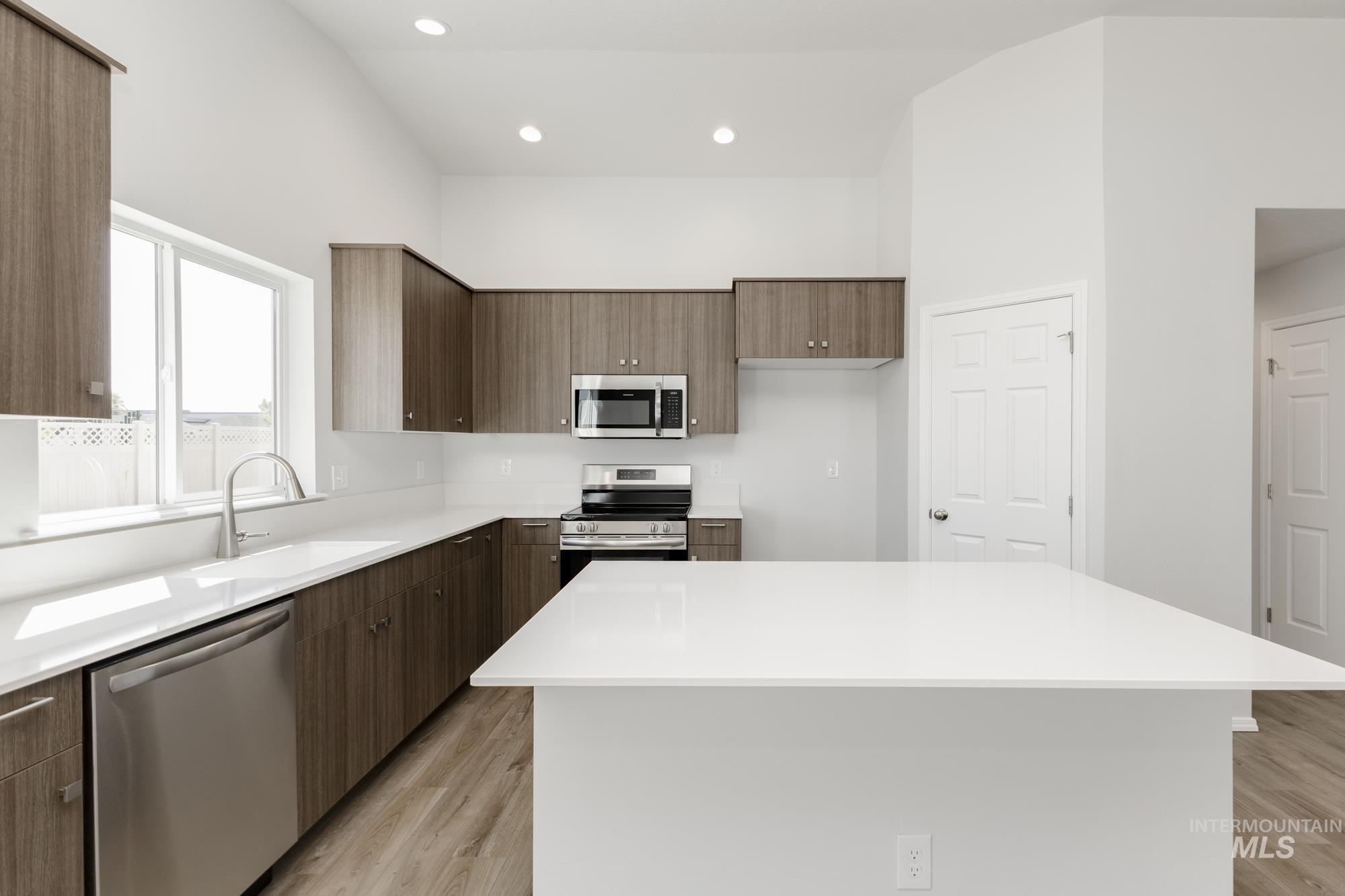 Kitchen featuring appliances with stainless steel finishes, modern cabinets, light wood finished floors, recessed lighting, and a kitchen island