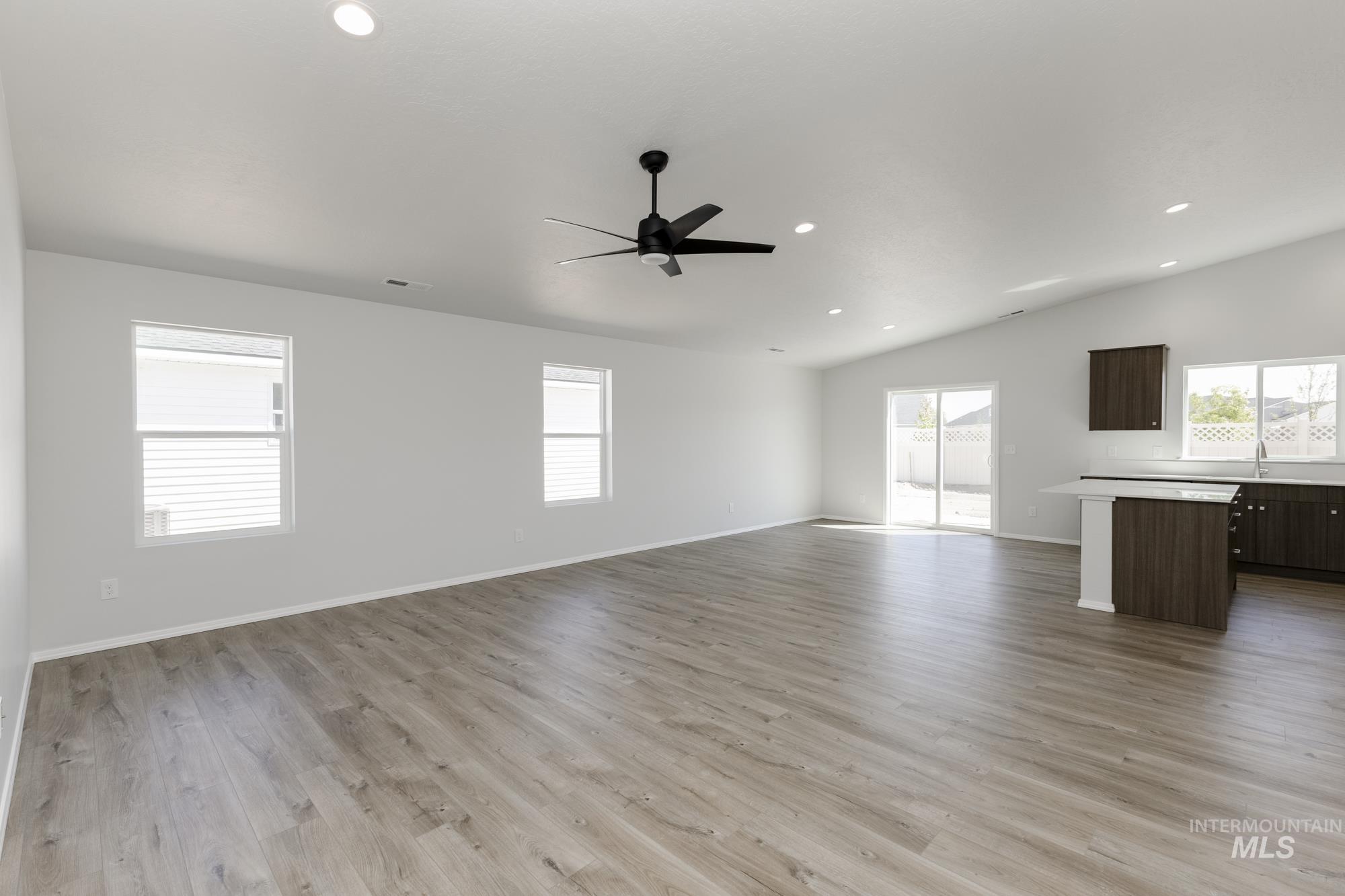 Unfurnished living room featuring light wood-style flooring, recessed lighting, a ceiling fan, and vaulted ceiling