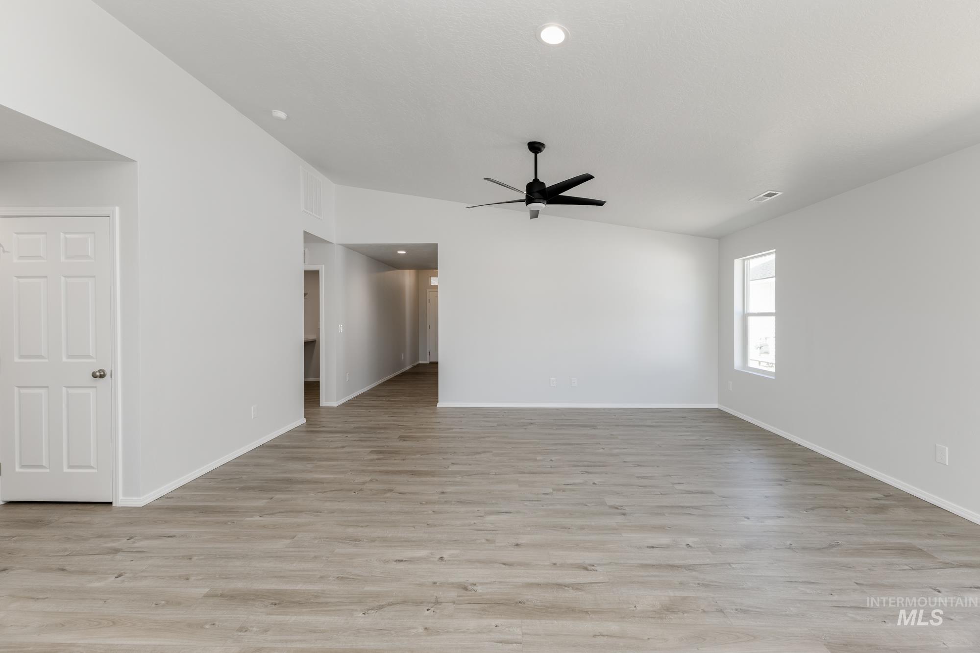 Empty room featuring vaulted ceiling, light wood-style flooring, a ceiling fan, and recessed lighting