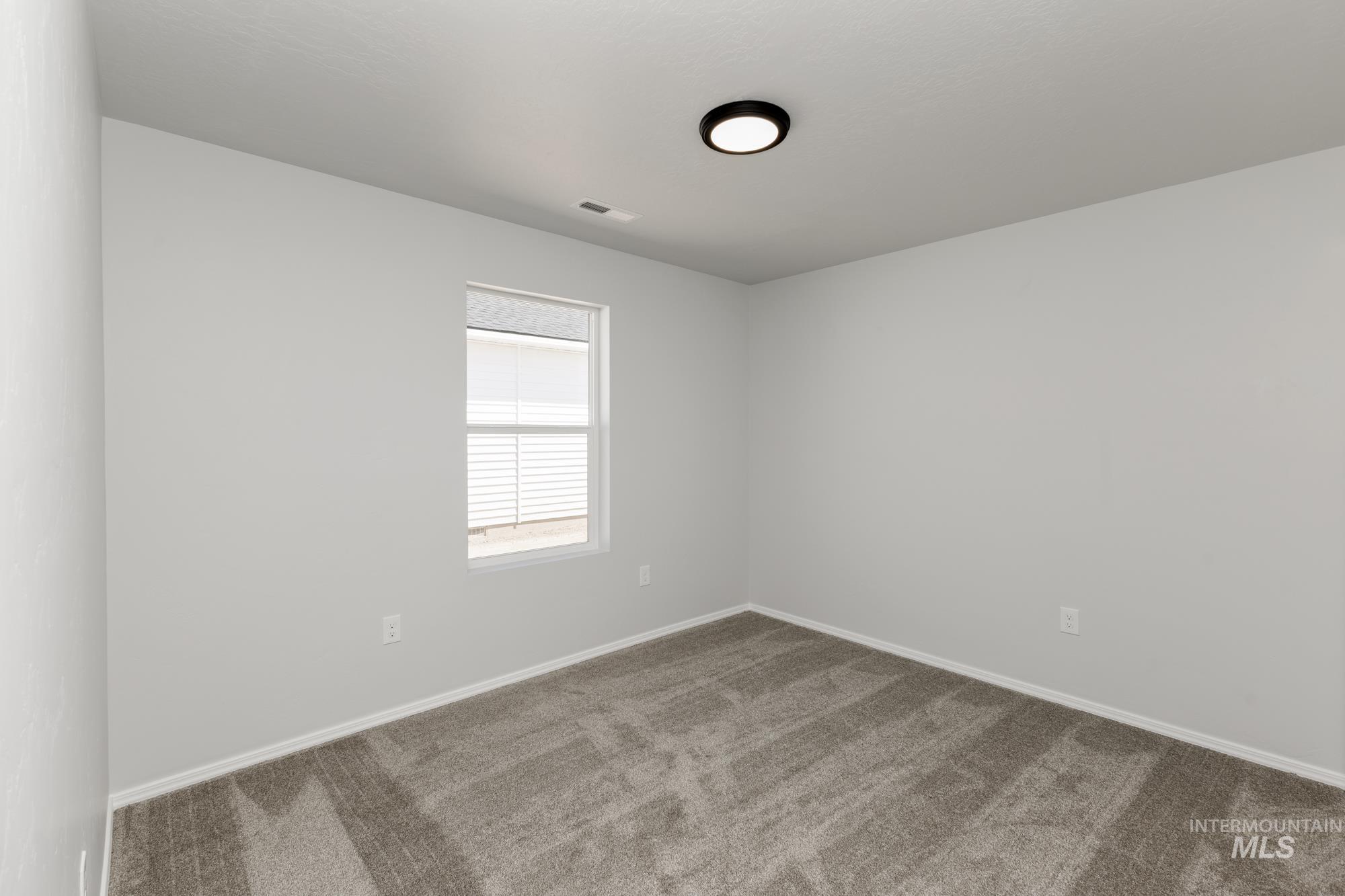Carpeted spare room featuring baseboards