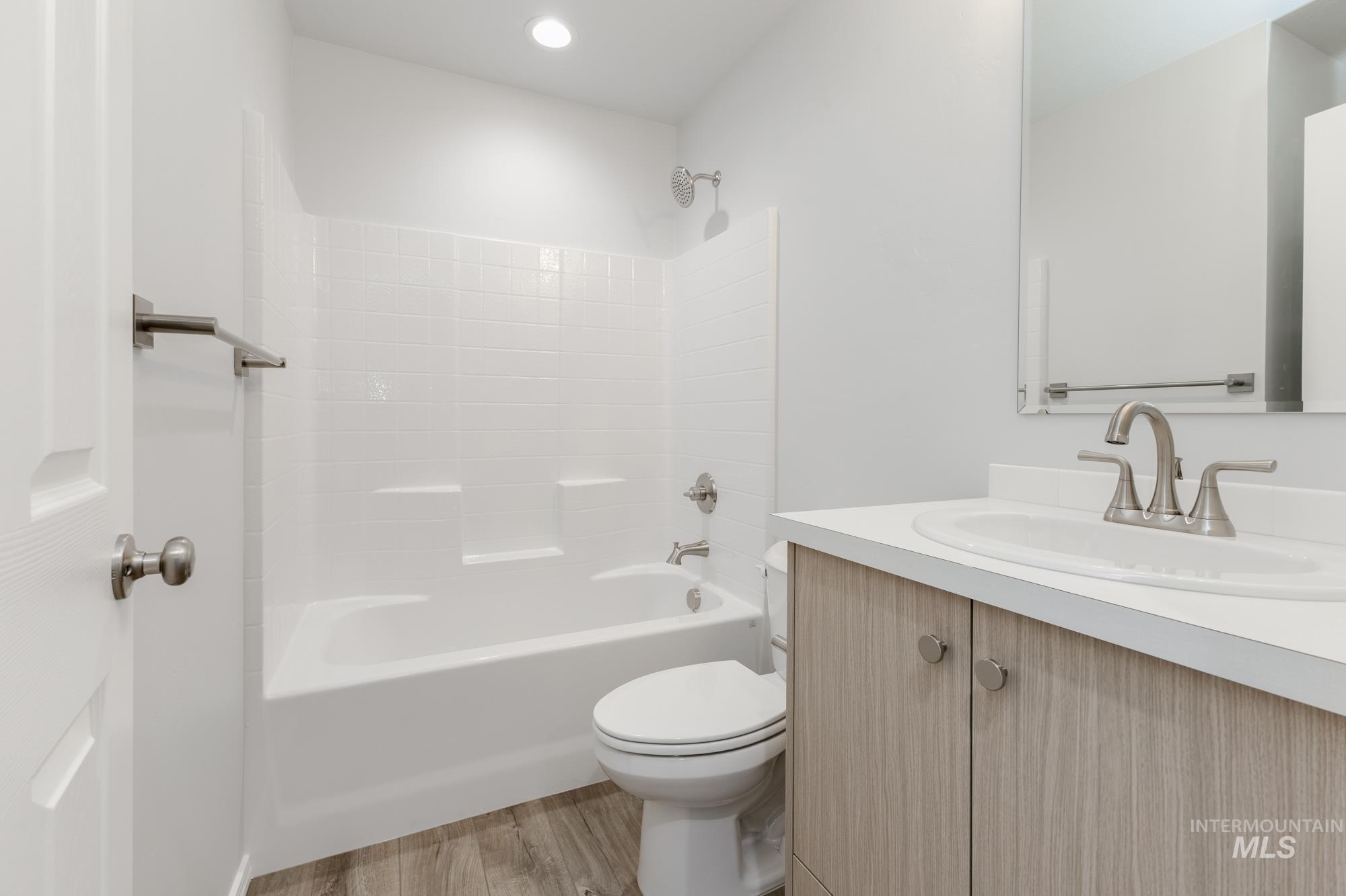 Bathroom with vanity, light wood-style flooring, shower / bathtub combination, and recessed lighting