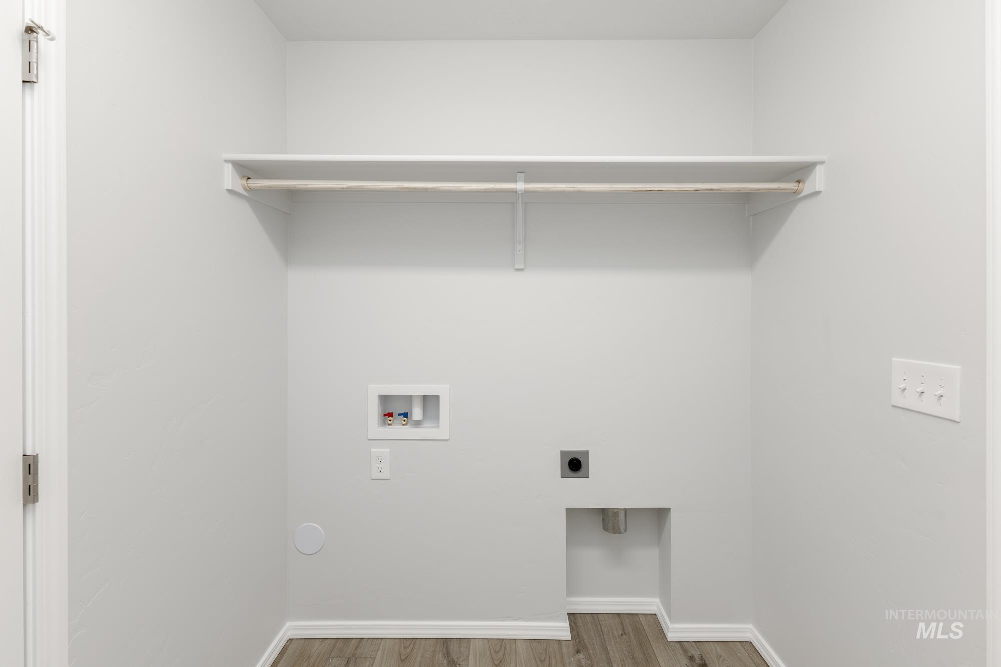 Washroom with light wood-style floors, hookup for an electric dryer, and washer hookup