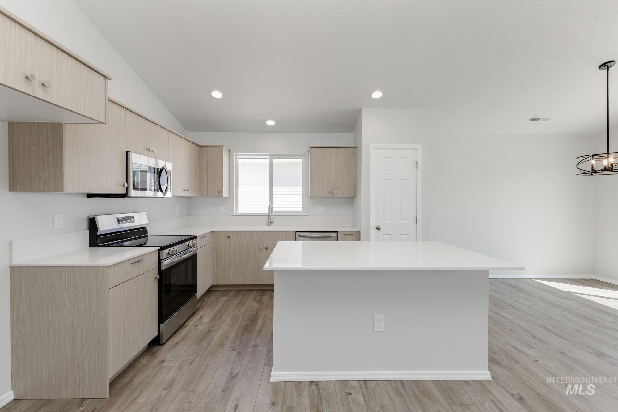 Kitchen featuring stainless steel appliances, a center island, recessed lighting, light wood-type flooring, and light brown cabinetry