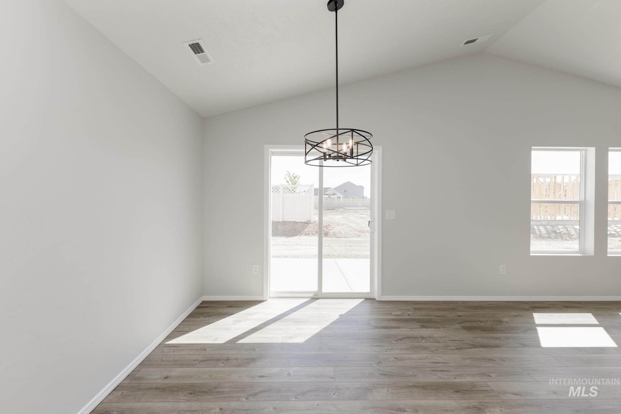 Unfurnished dining area featuring light wood-style floors, vaulted ceiling, and a chandelier