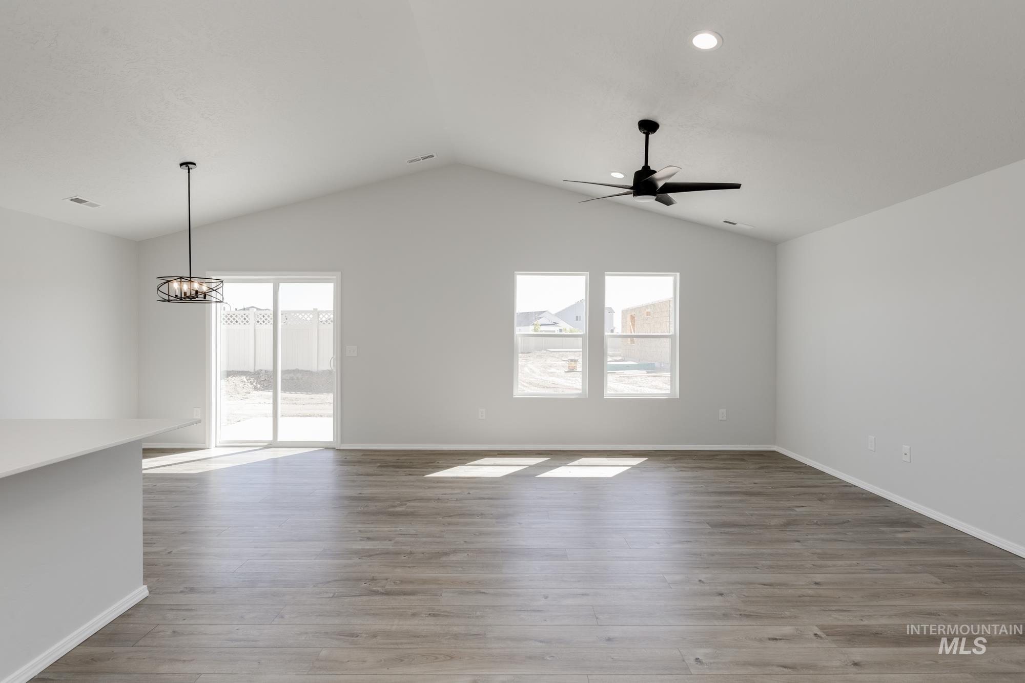 Spare room featuring light wood-style floors, lofted ceiling, recessed lighting, a ceiling fan, and a chandelier