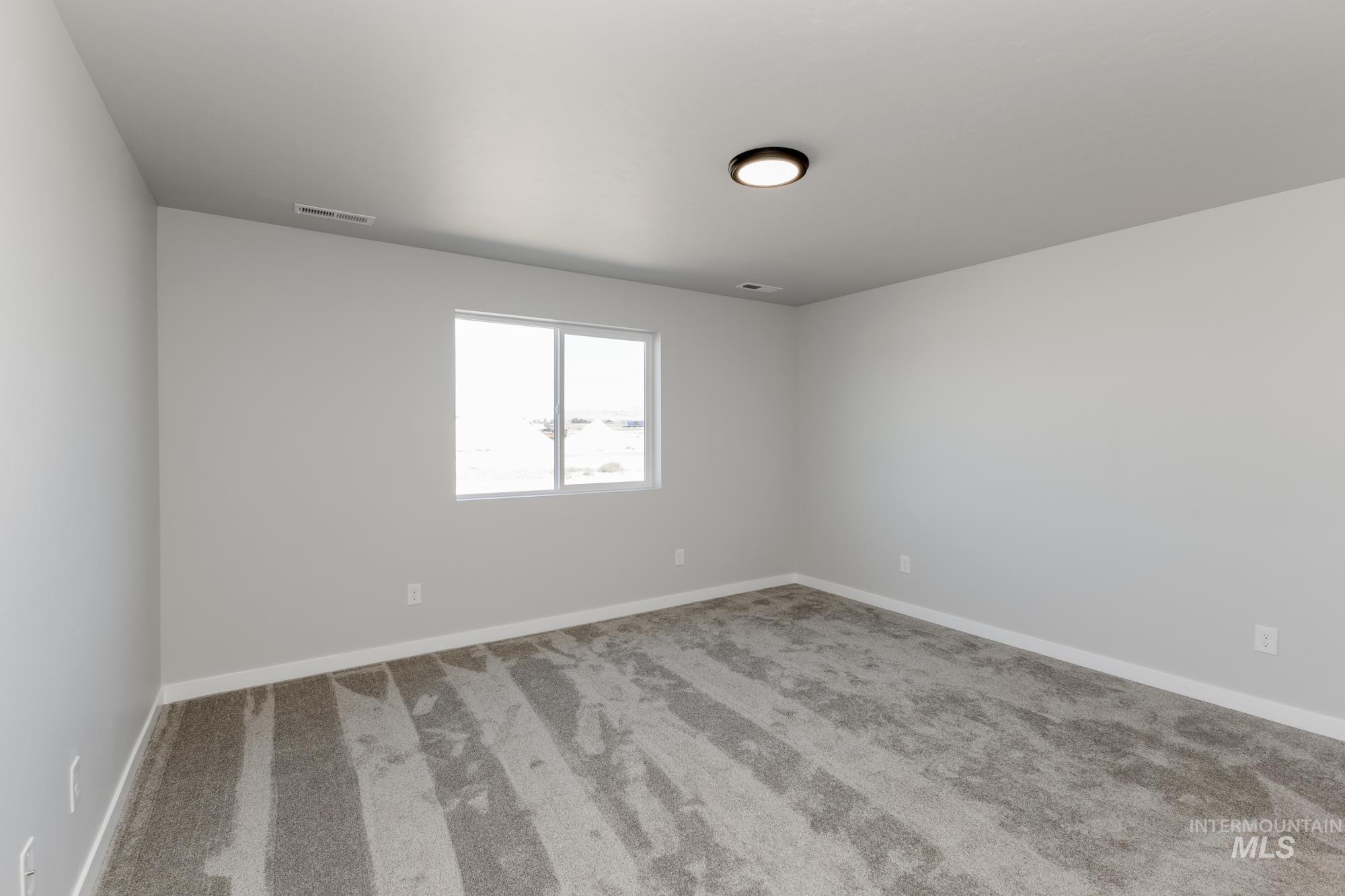 Spare room featuring carpet floors and baseboards