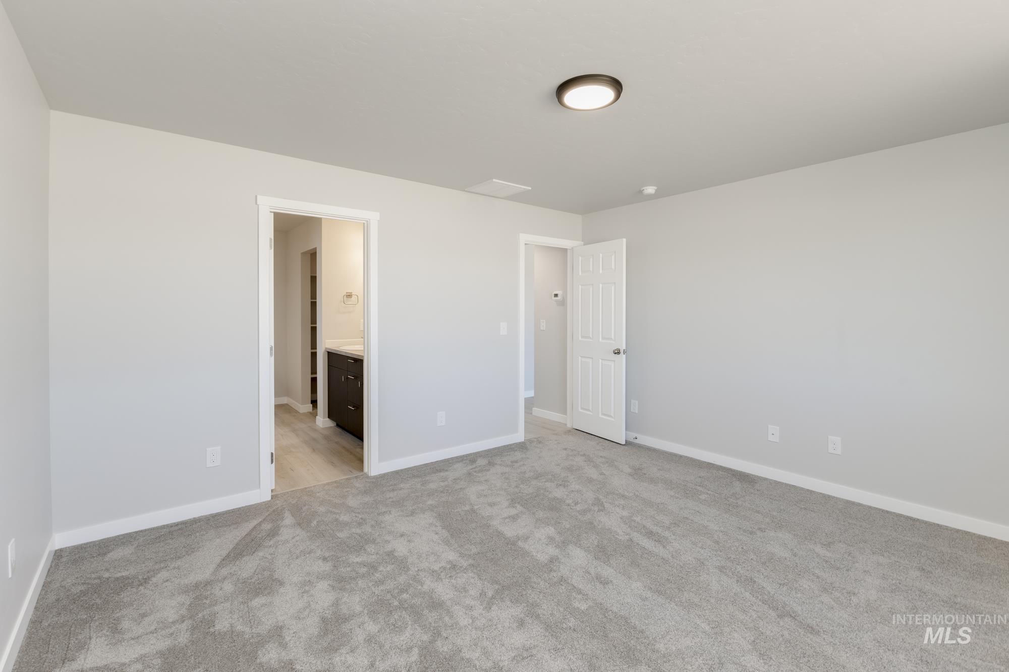 Unfurnished bedroom featuring light colored carpet and ensuite bath