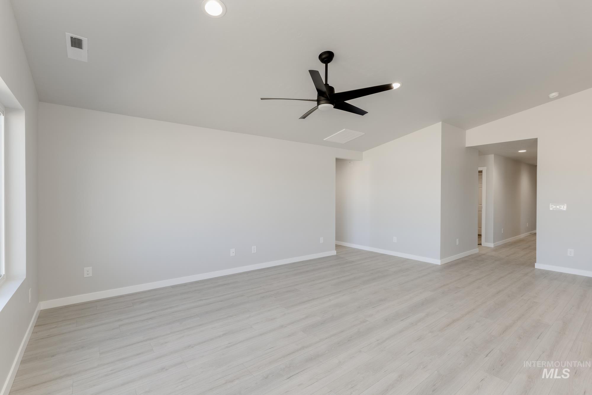 Empty room featuring light wood-style floors, recessed lighting, ceiling fan, and vaulted ceiling