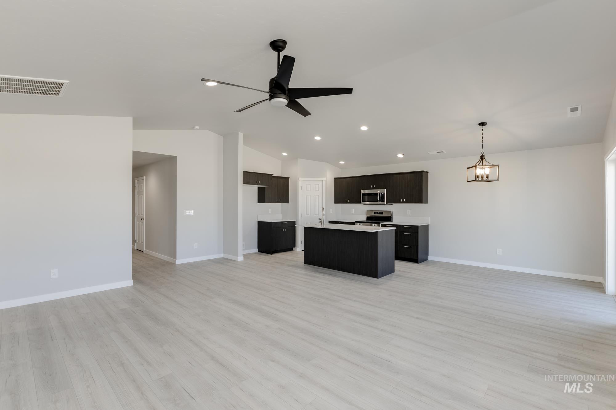 Kitchen with open floor plan, light countertops, light wood-style floors, lofted ceiling, and appliances with stainless steel finishes