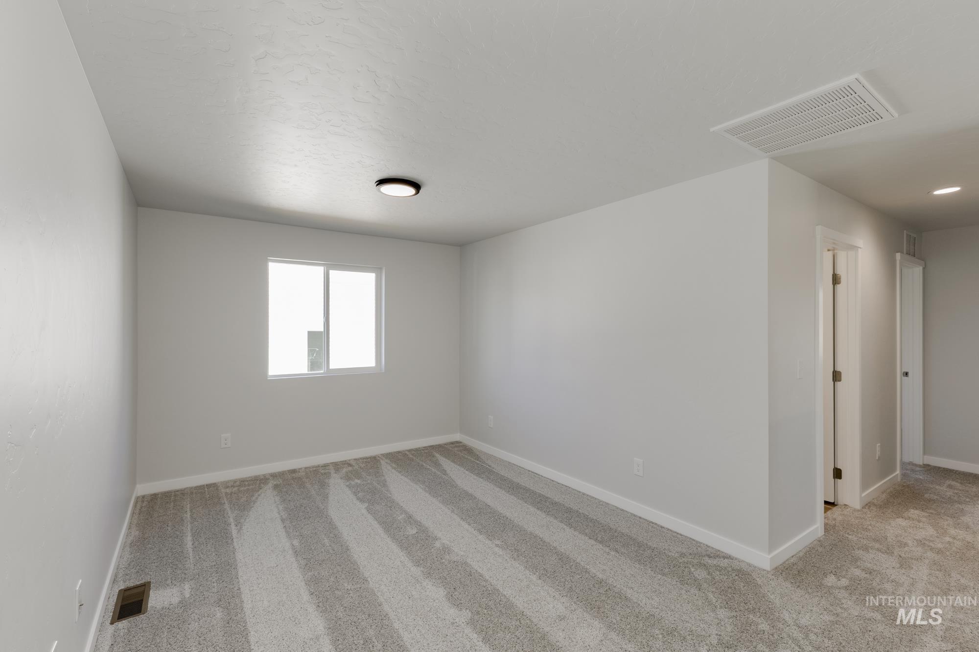 Unfurnished room featuring light carpet and baseboards