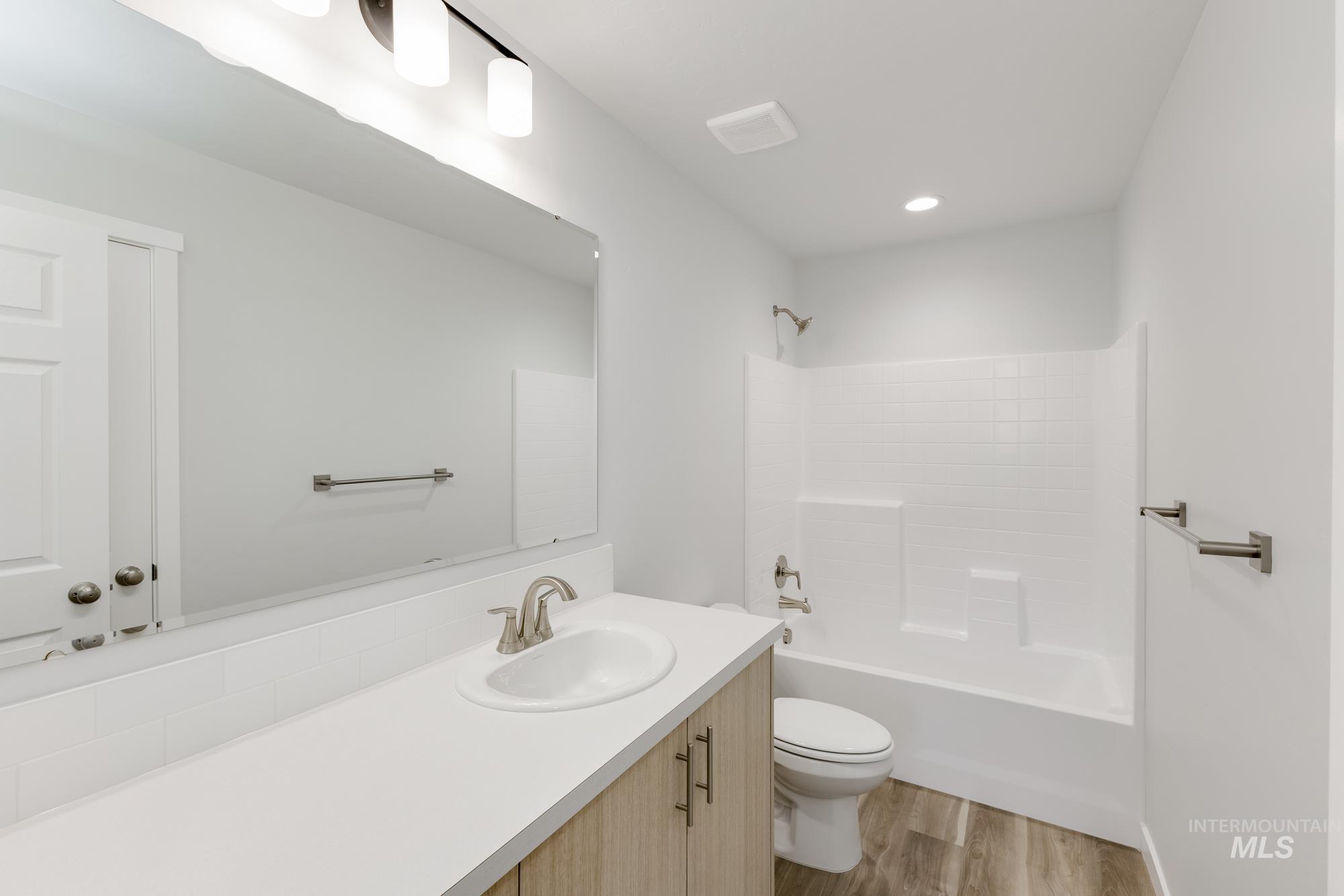 Bathroom featuring vanity, light wood-style floors, bathing tub / shower combination, and recessed lighting