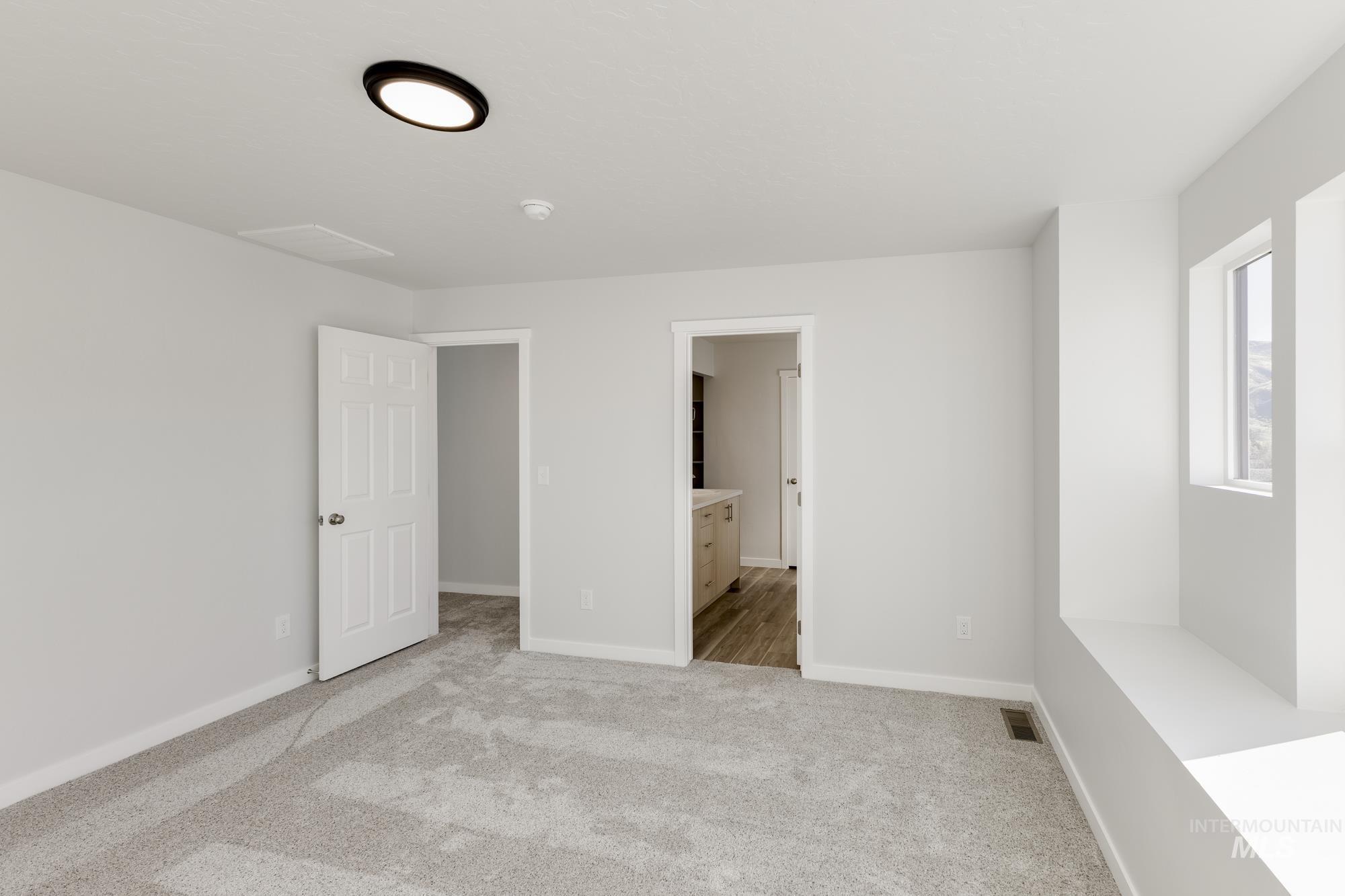 Unfurnished bedroom with light colored carpet and ensuite bathroom