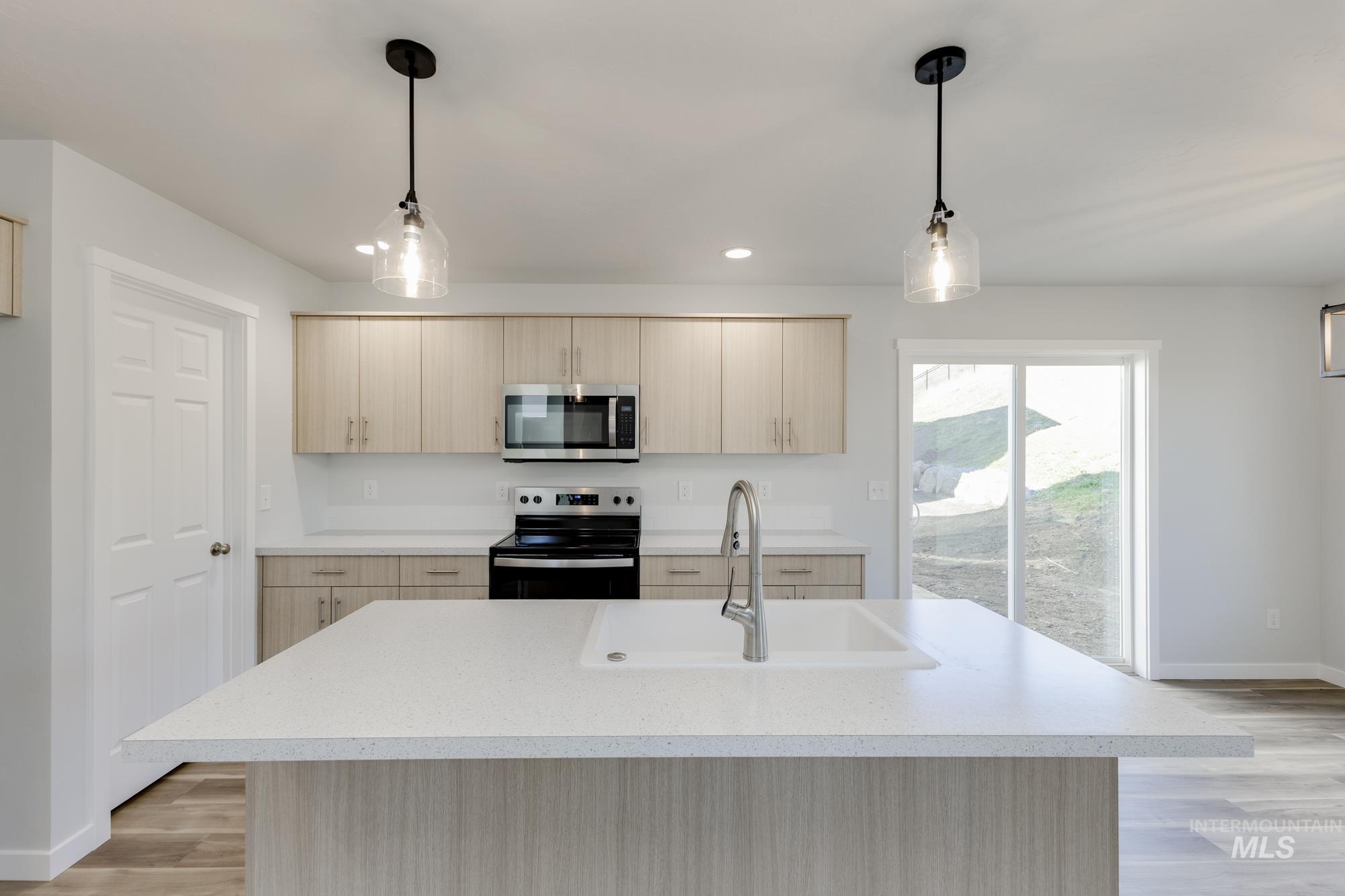 Kitchen with light brown cabinetry, light wood-style flooring, stainless steel appliances, and recessed lighting