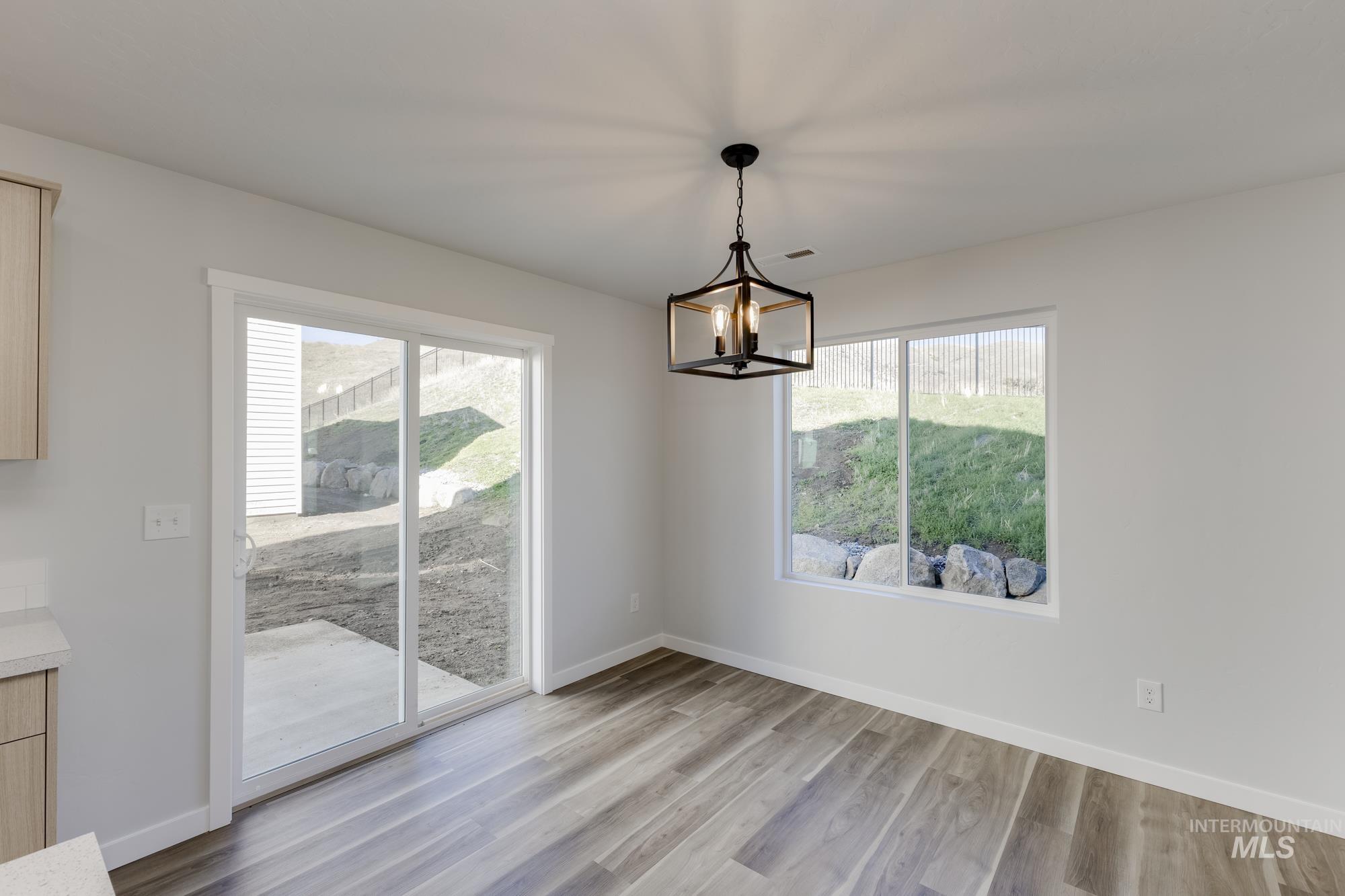 Unfurnished dining area featuring light wood-style flooring and a chandelier