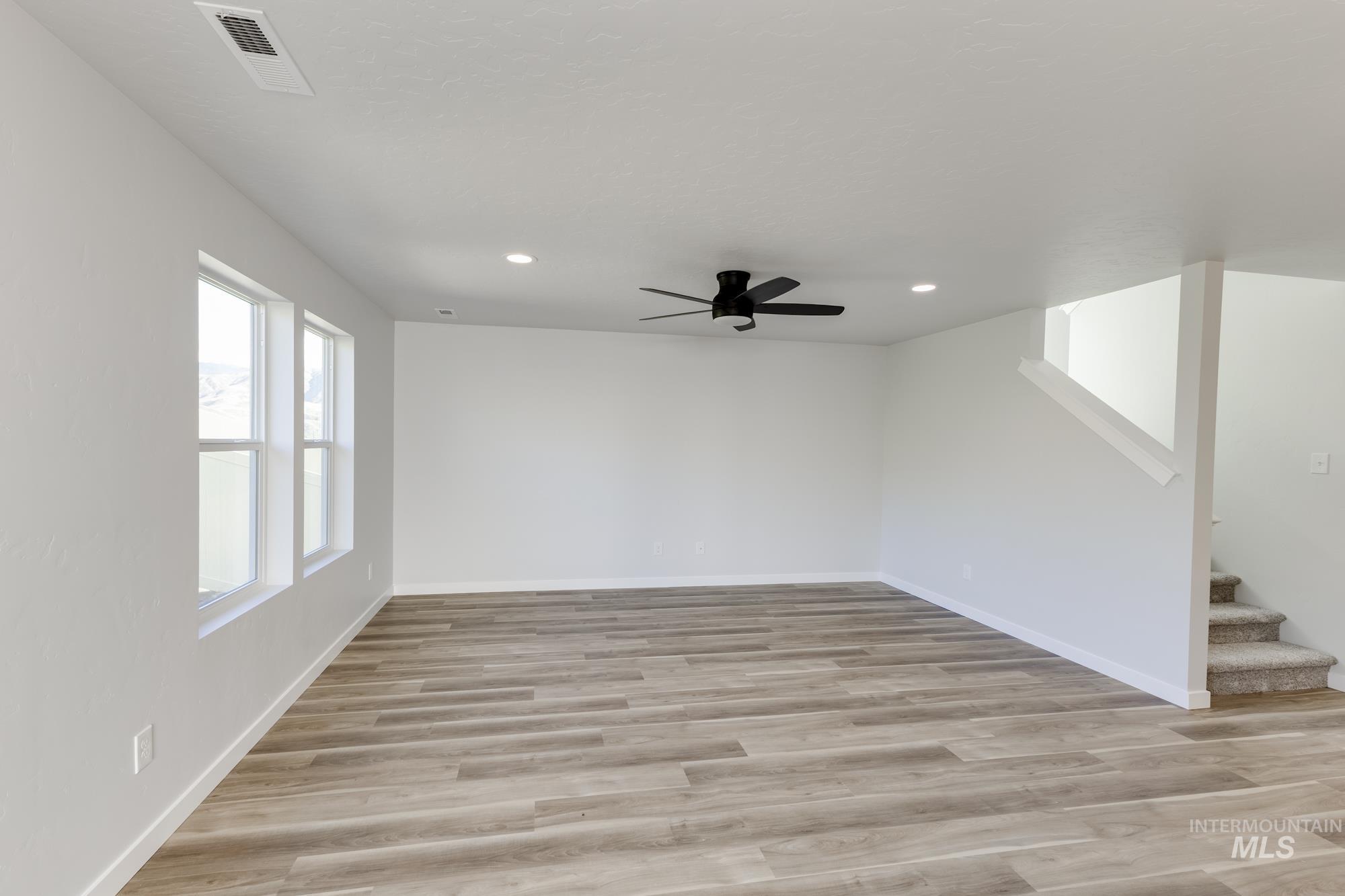 Spare room with light wood-type flooring, ceiling fan, recessed lighting, and stairs
