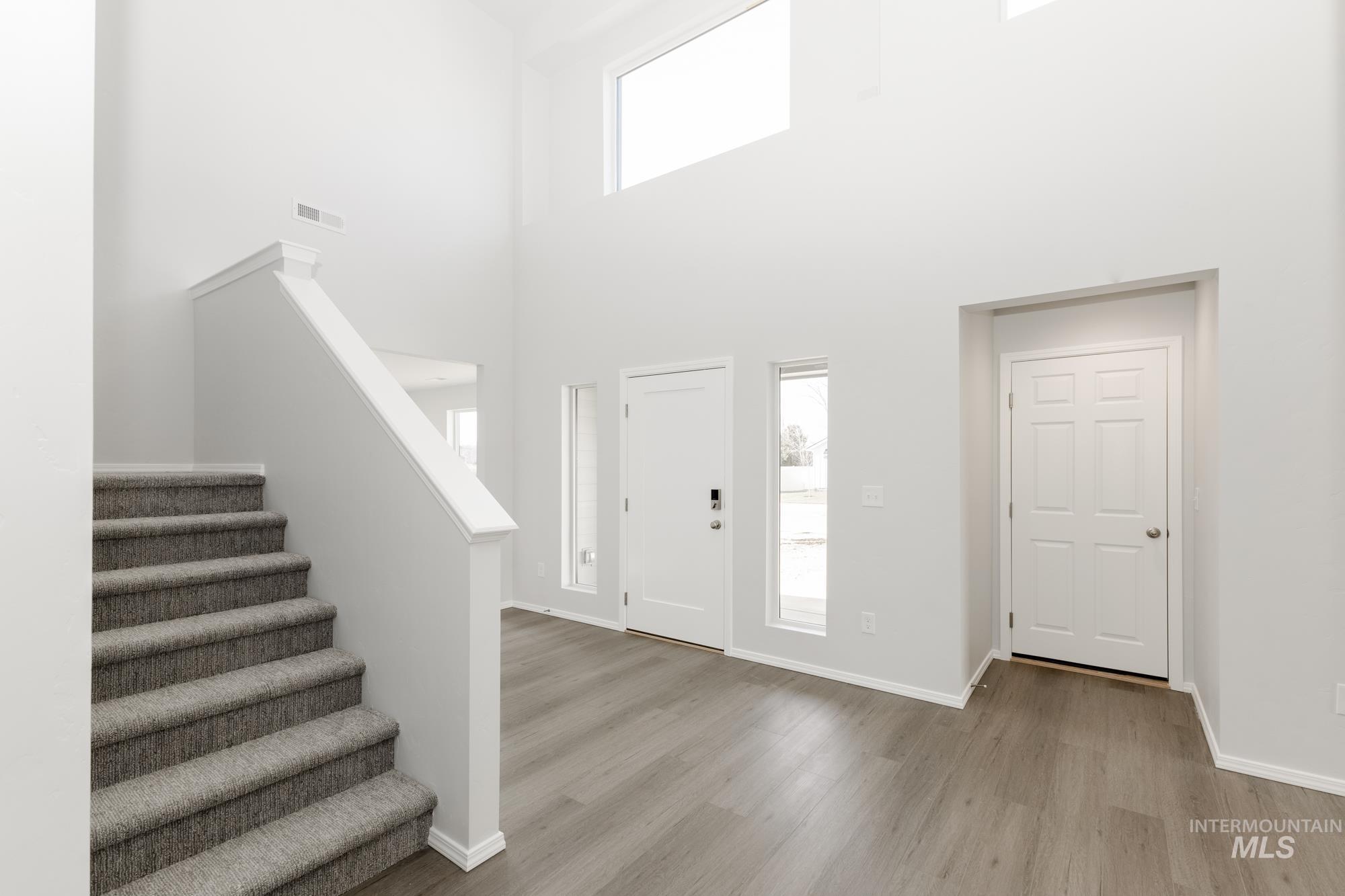 Entrance foyer featuring stairway, light wood-style floors, and a high ceiling