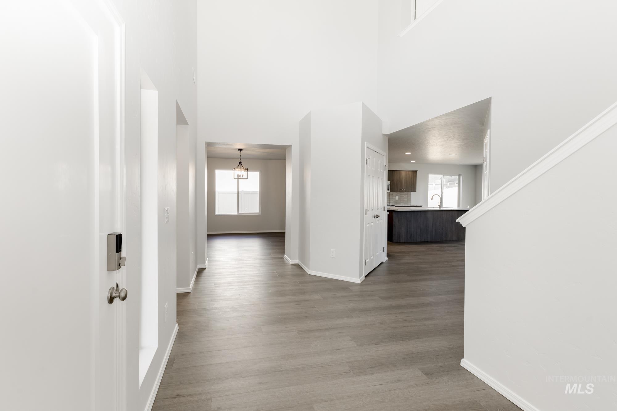 Hallway with light wood-style flooring, a chandelier, and a towering ceiling