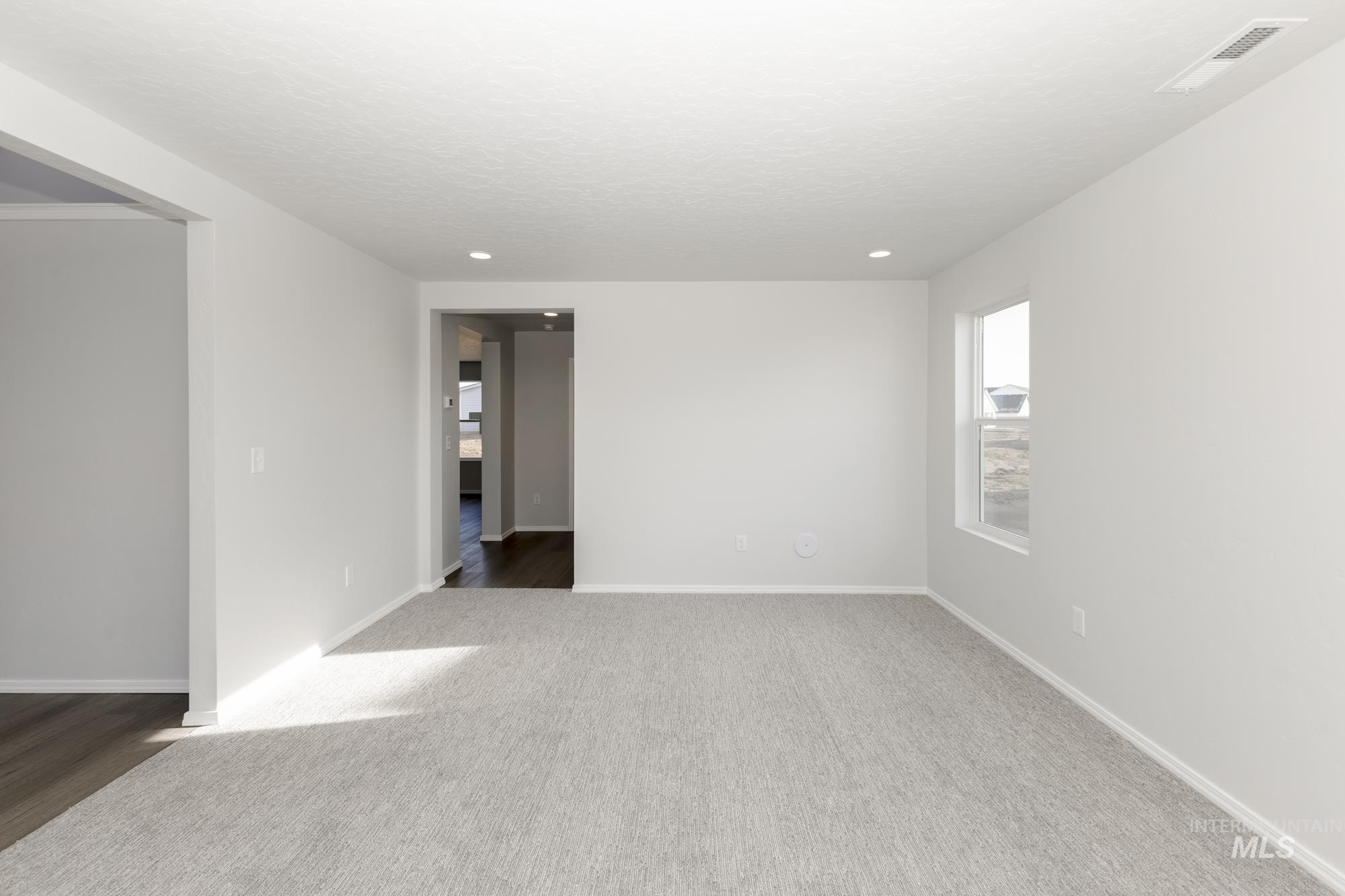 Carpeted empty room with a textured ceiling and recessed lighting