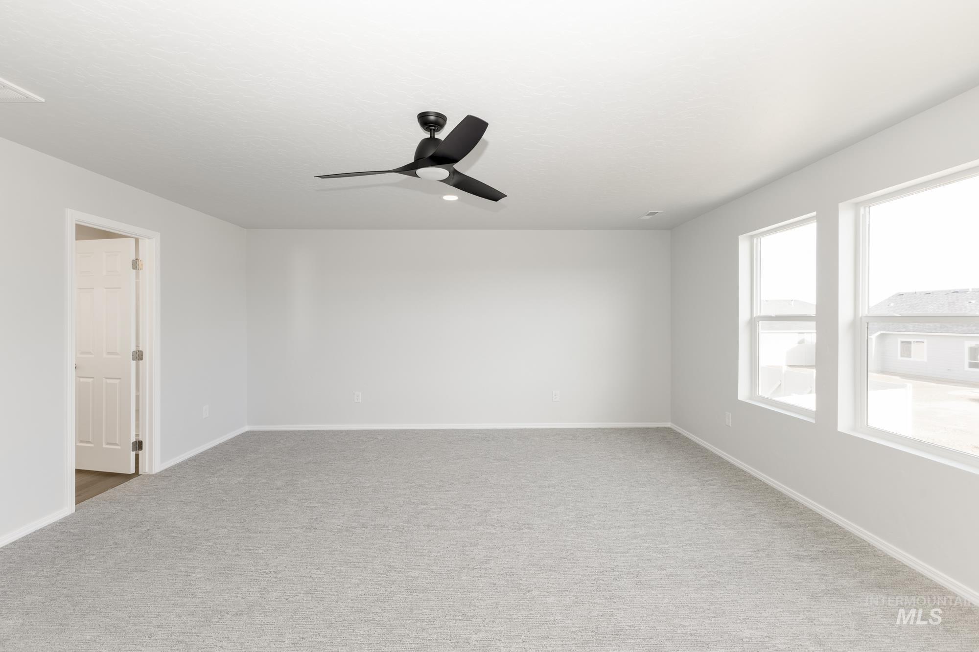 Carpeted empty room with baseboards and a ceiling fan
