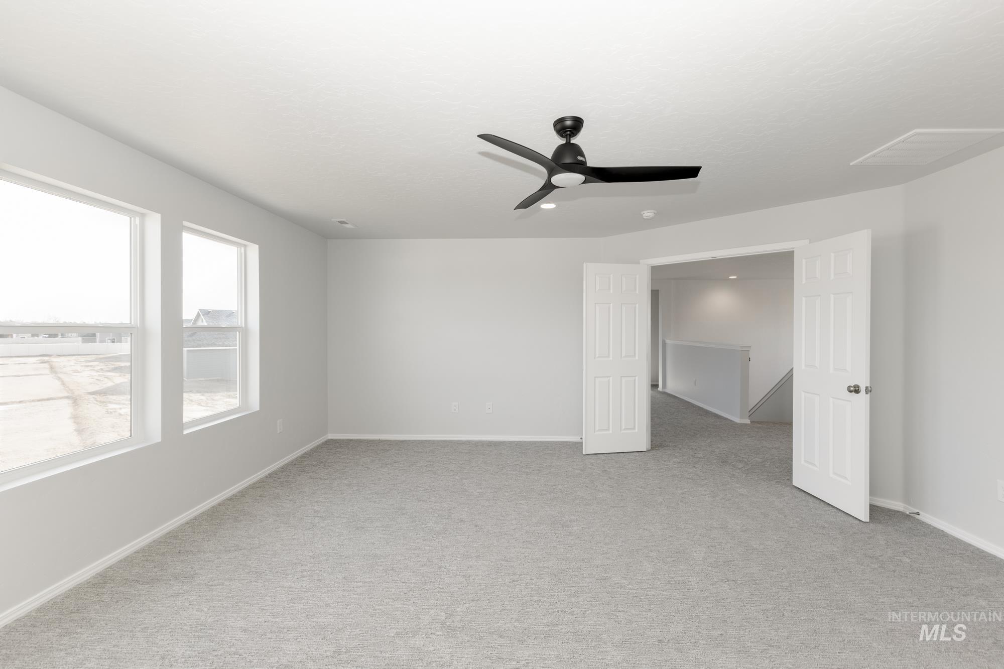 Empty room featuring light colored carpet and a ceiling fan