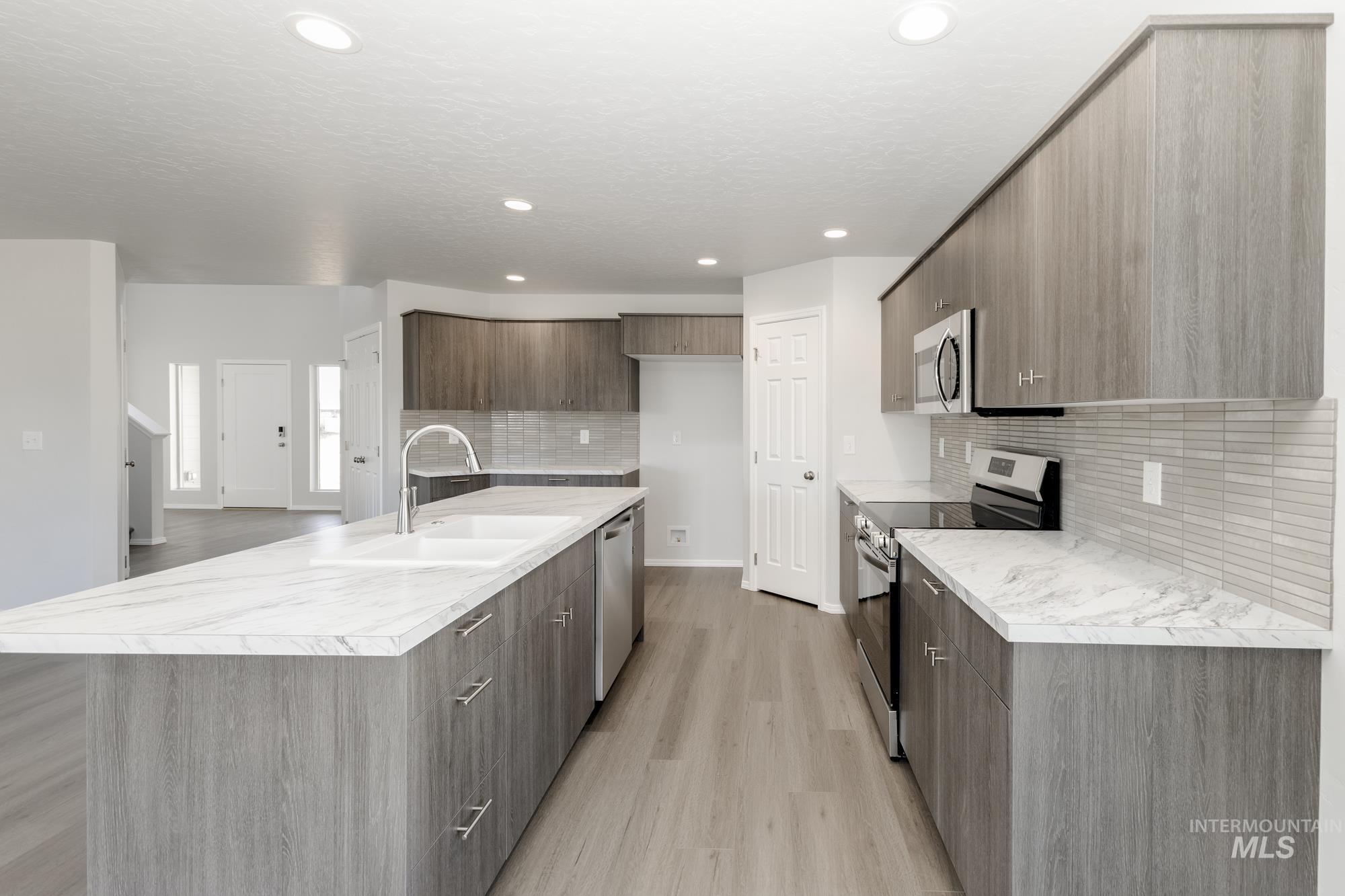Kitchen with light countertops, appliances with stainless steel finishes, modern cabinets, light wood-type flooring, and recessed lighting