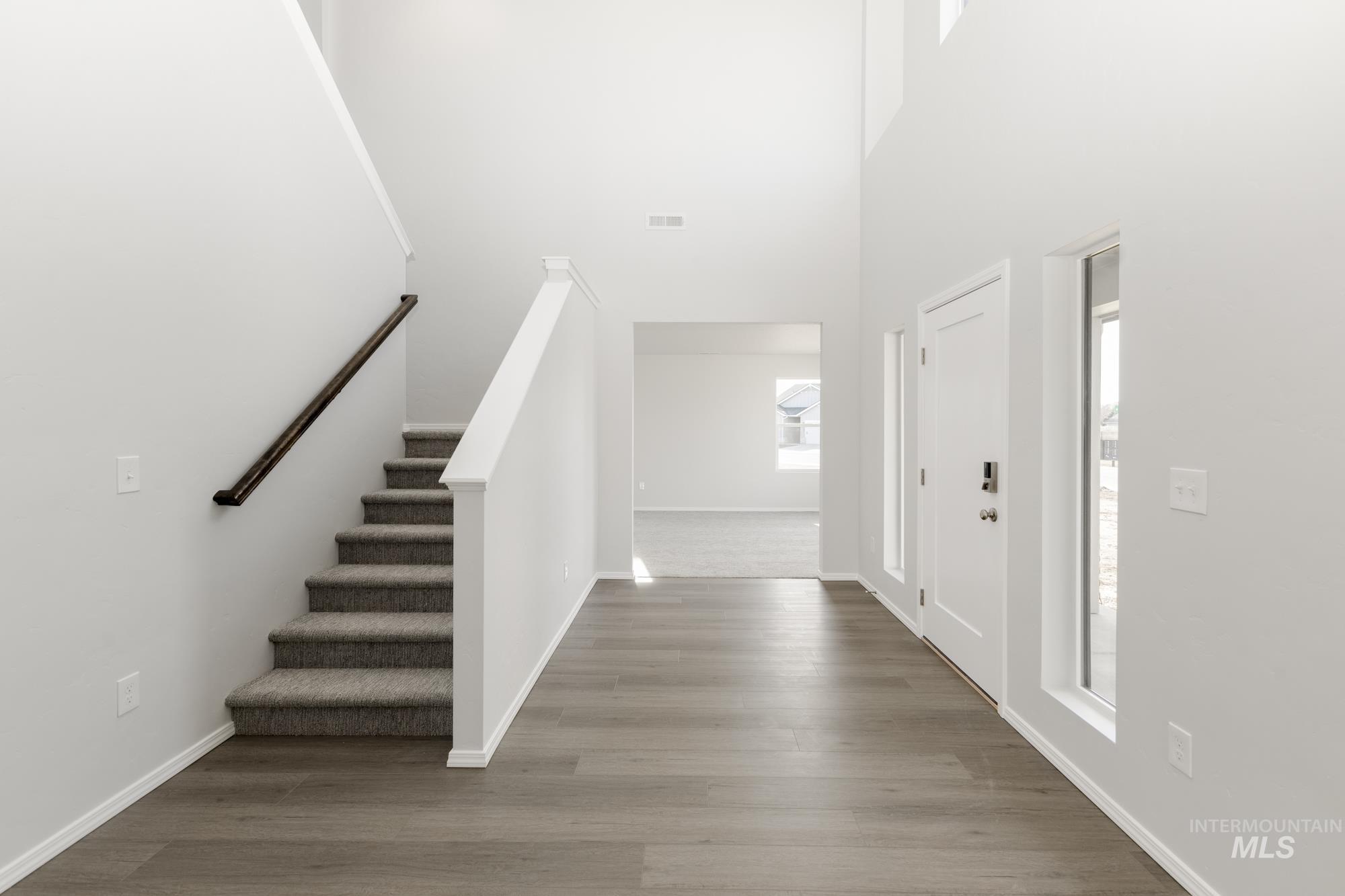 Entrance foyer with stairway, wood finished floors, and a high ceiling