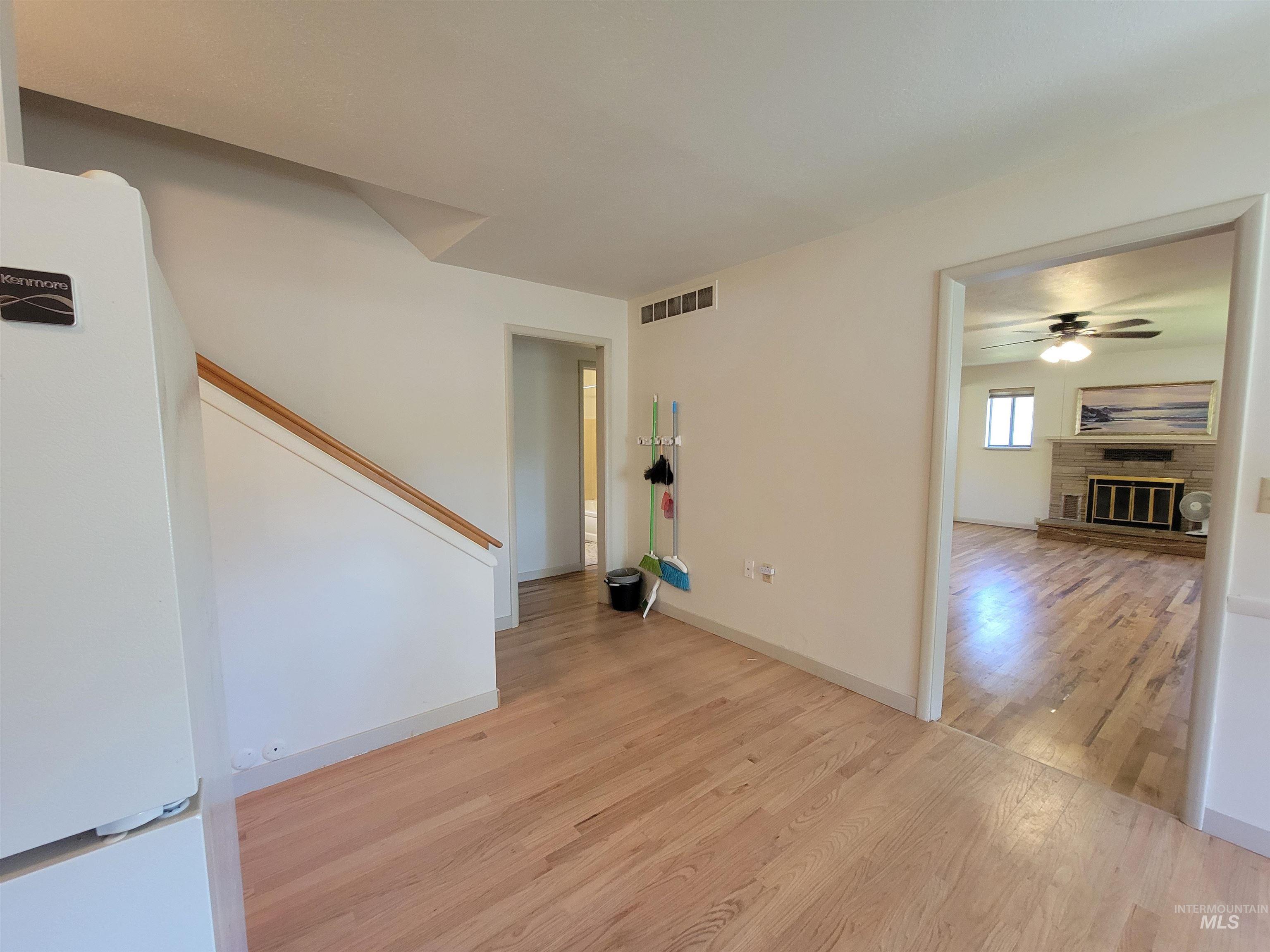 Empty room featuring a glass covered fireplace, light wood-style flooring, and ceiling fan