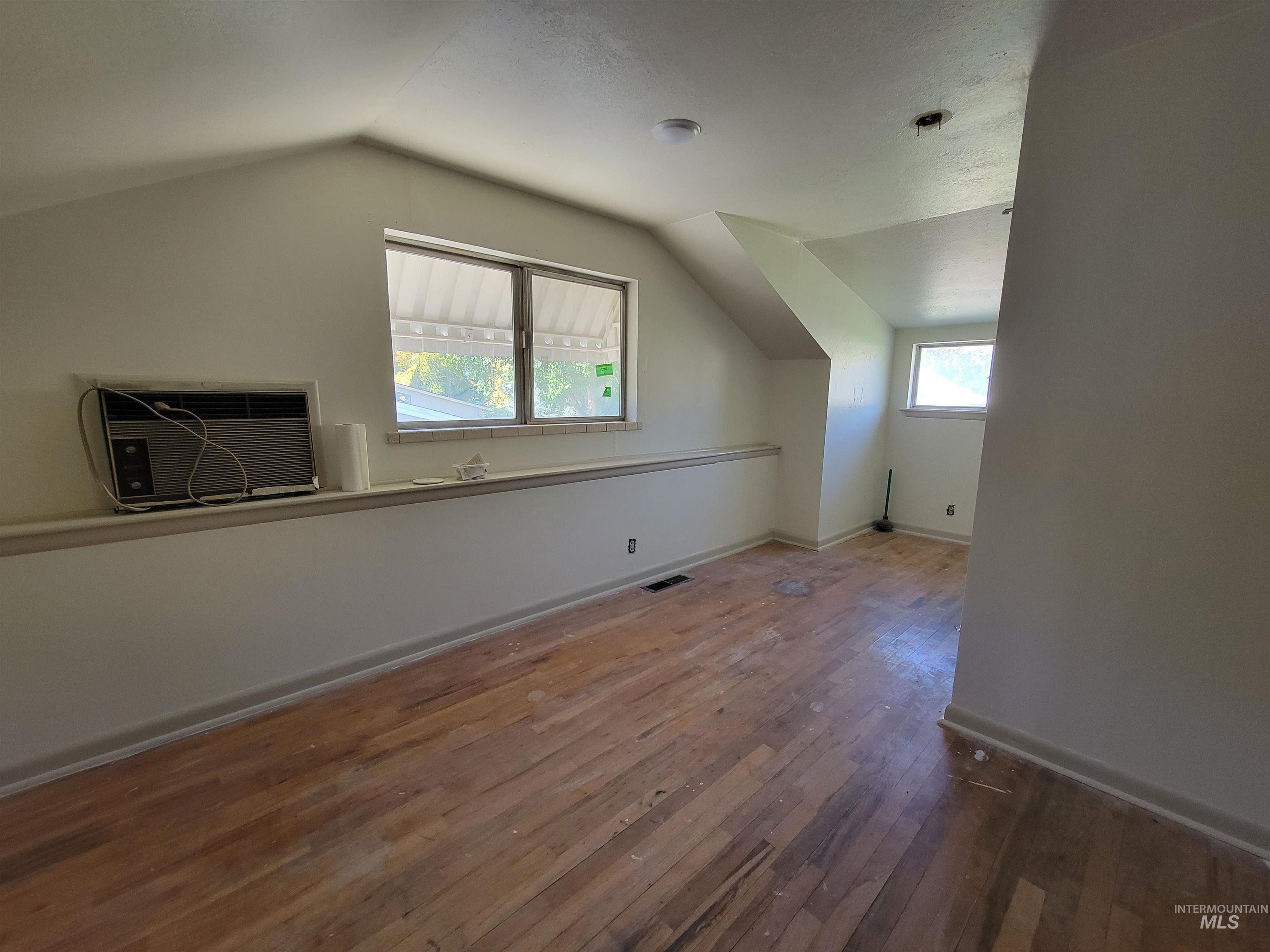 Bonus room featuring vaulted ceiling, wood-type flooring, and a wall mounted air conditioner