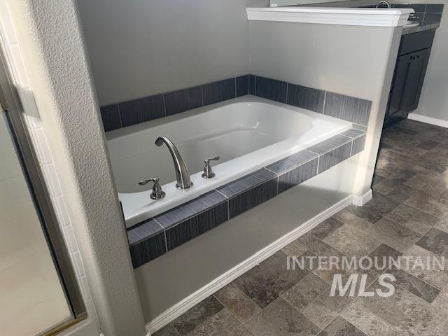 Bathroom featuring stone finish flooring and a garden tub