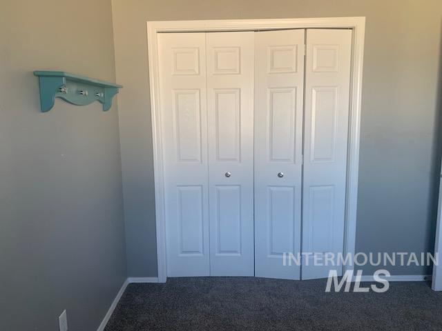 Unfurnished bedroom with dark colored carpet and a closet