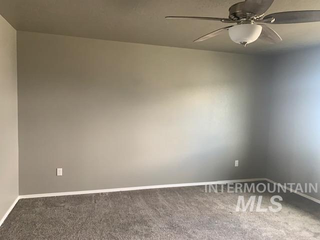 Carpeted spare room with a ceiling fan and baseboards