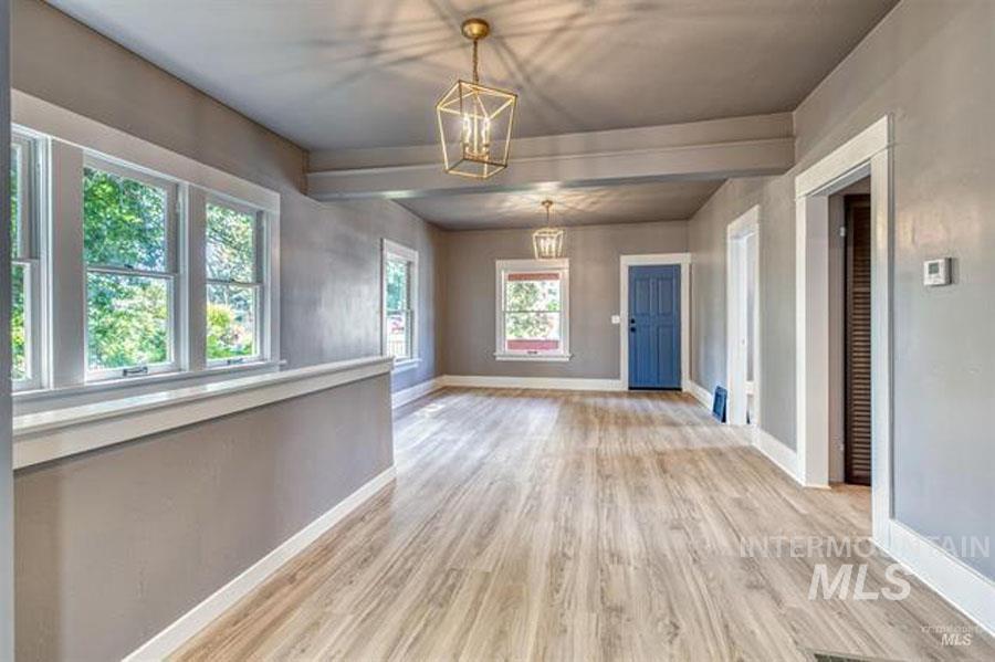 Unfurnished room with light wood-style flooring and a chandelier