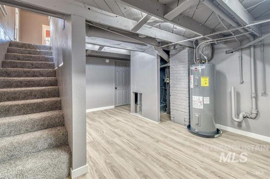 Basement with water heater, wood finished floors, and stairway