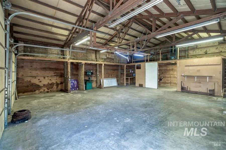 Misc room featuring concrete flooring, a garage, and vaulted ceiling