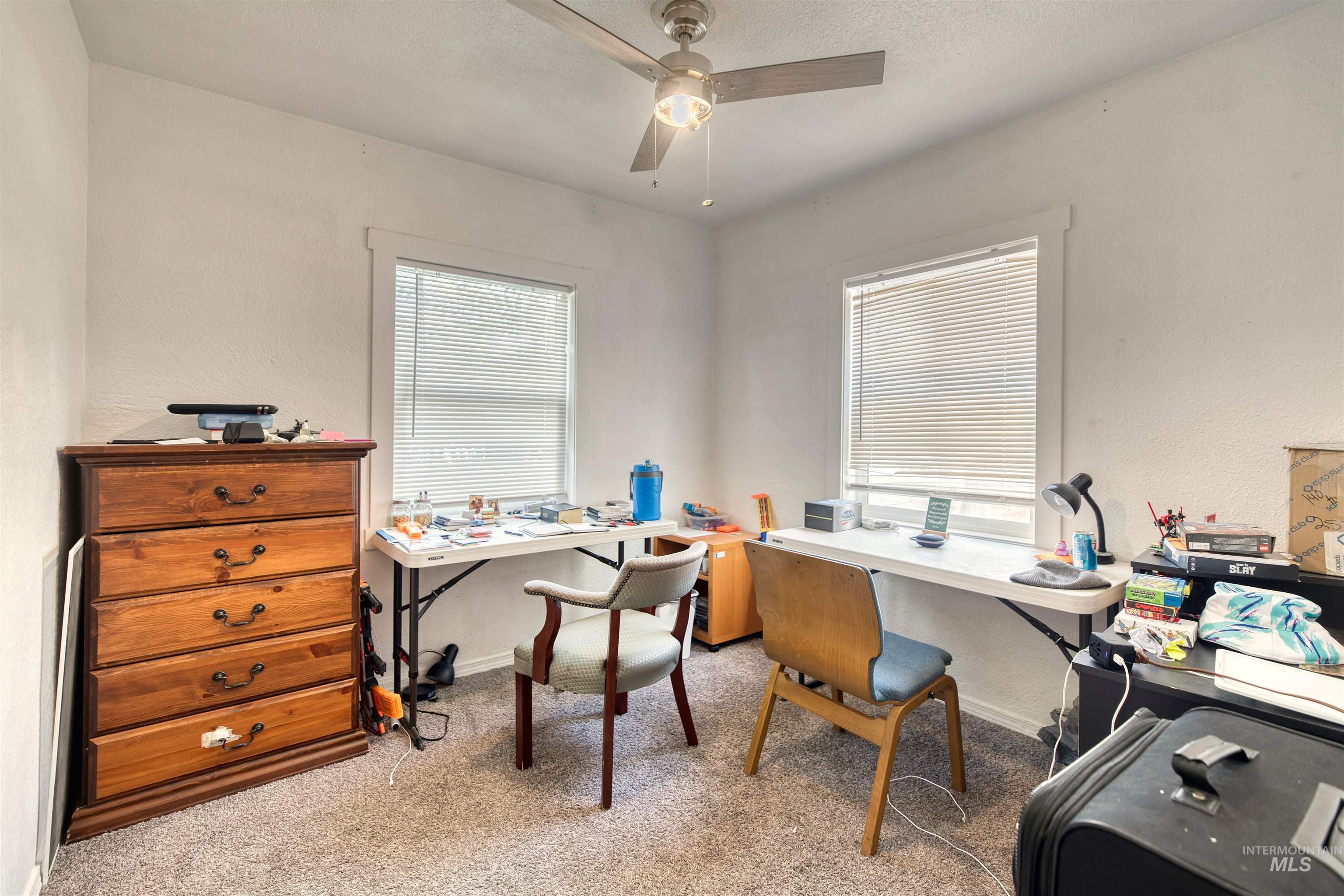 Office space with light colored carpet, a ceiling fan, a textured wall, and a textured ceiling