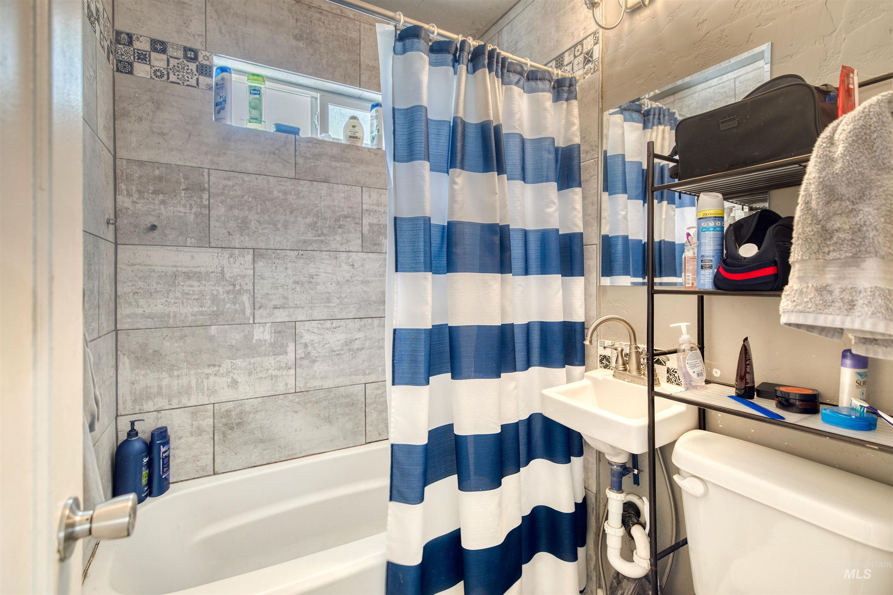 Bathroom with toilet and shower / bath combo with shower curtain