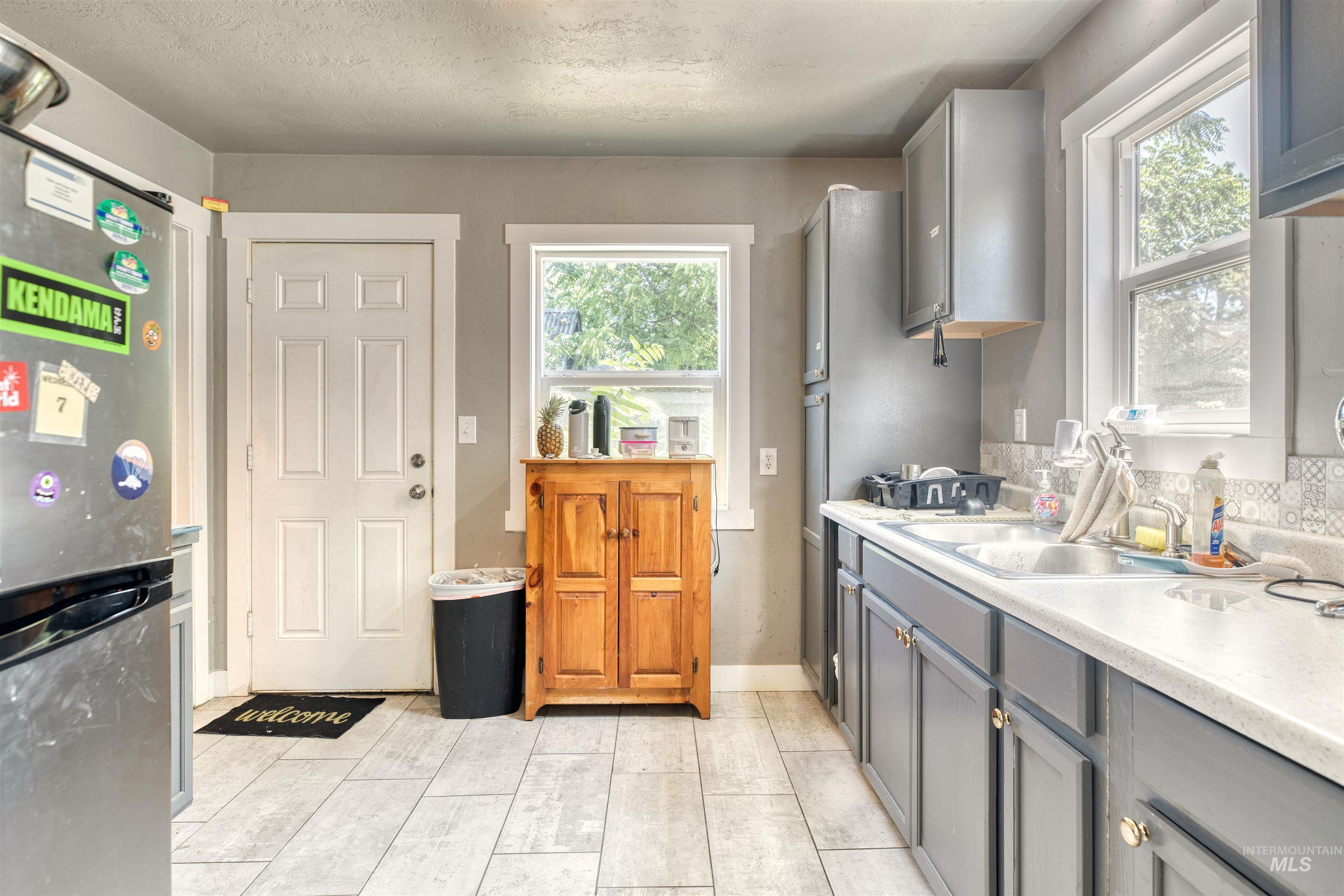 Kitchen with light countertops, freestanding refrigerator, gray cabinets, healthy amount of natural light, and a textured ceiling