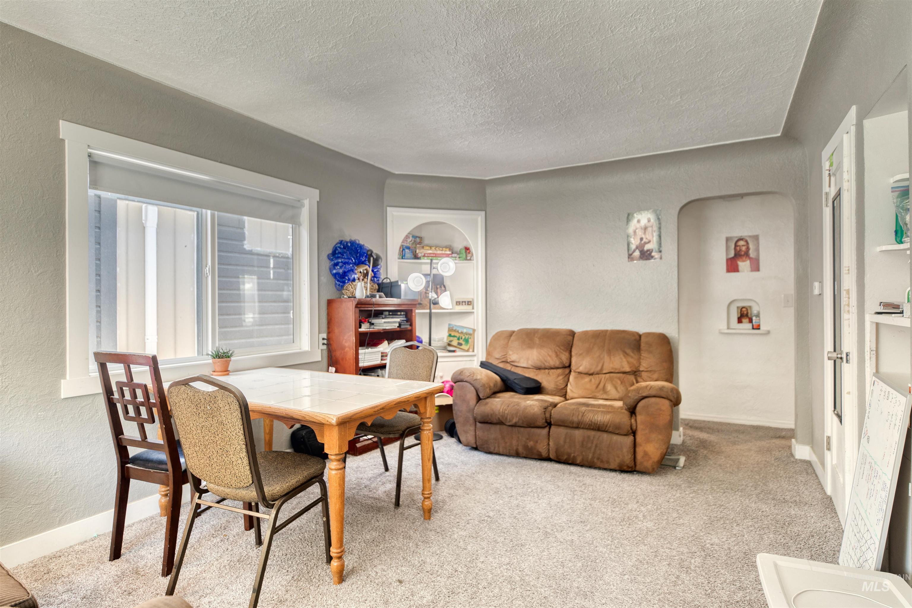 Carpeted dining area with built in features, a textured wall, arched walkways, and a textured ceiling