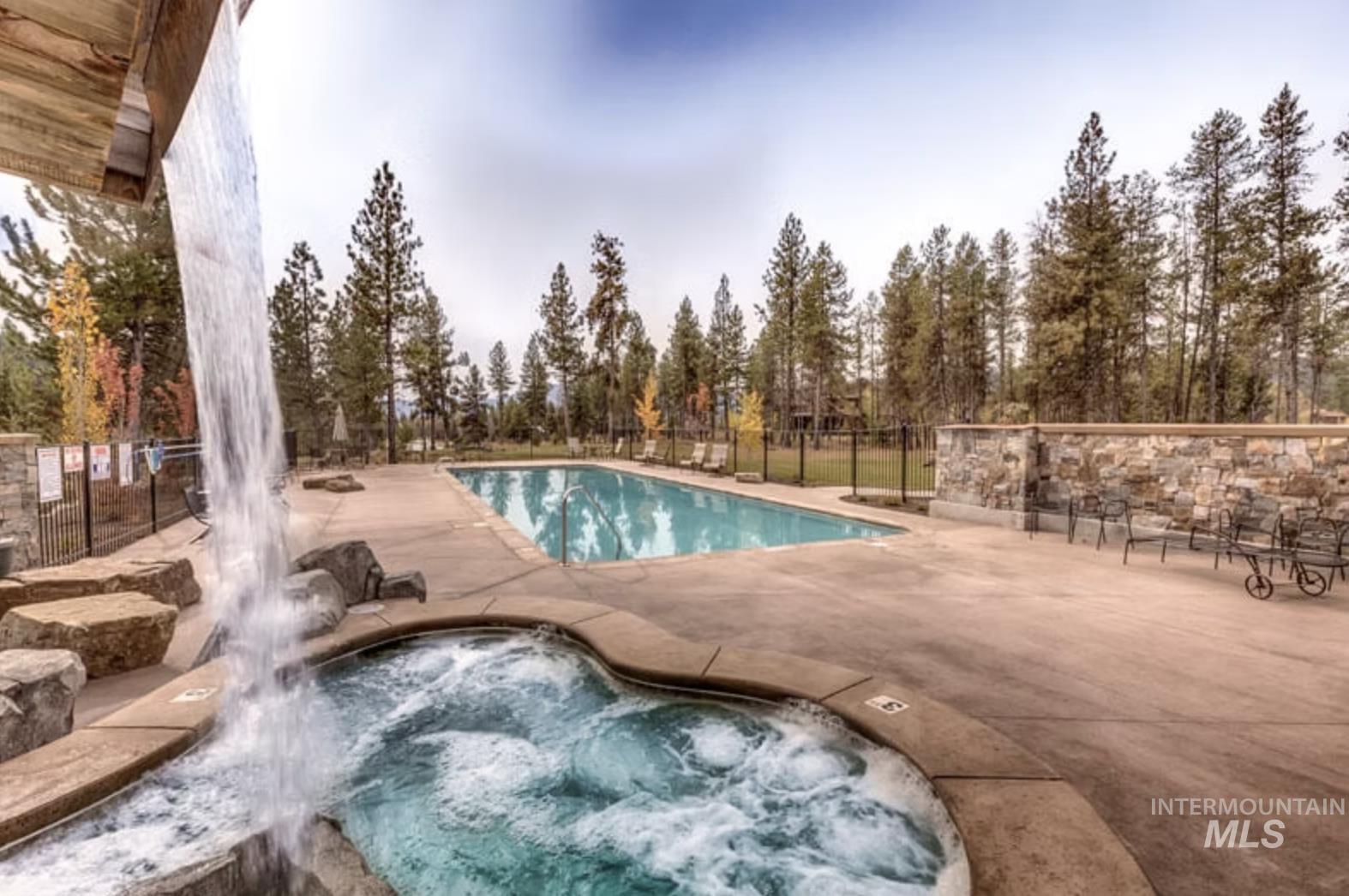 Community pool featuring a community hot tub, a patio area, and view of scattered trees