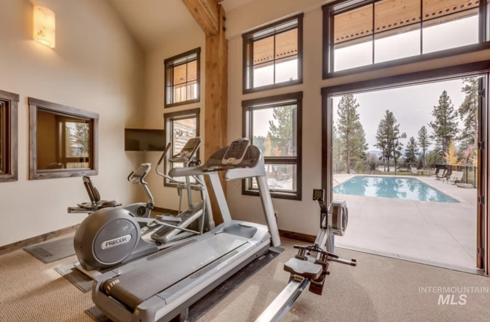 Workout area featuring high vaulted ceiling and beam ceiling
