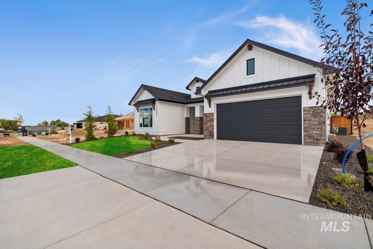 Modern farmhouse with a standing seam roof, a metal roof, driveway, and stone siding