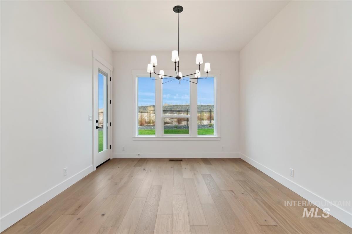Unfurnished dining area featuring light wood-type flooring and a chandelier
