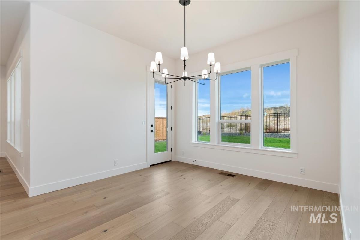 Unfurnished dining area featuring light wood finished floors and a chandelier
