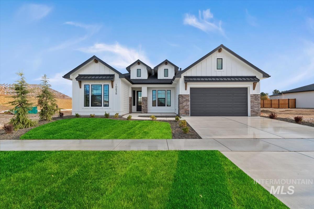 Modern farmhouse featuring a standing seam roof, a metal roof, concrete driveway, and board and batten siding