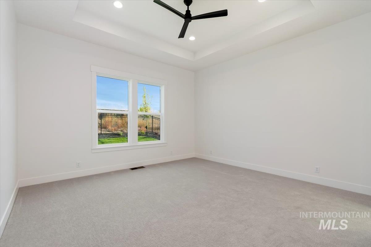 Unfurnished room with a raised ceiling, a ceiling fan, light colored carpet, and recessed lighting