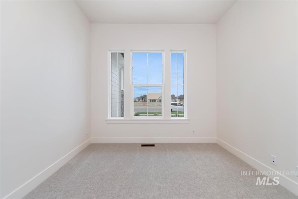 Empty room featuring light carpet and baseboards
