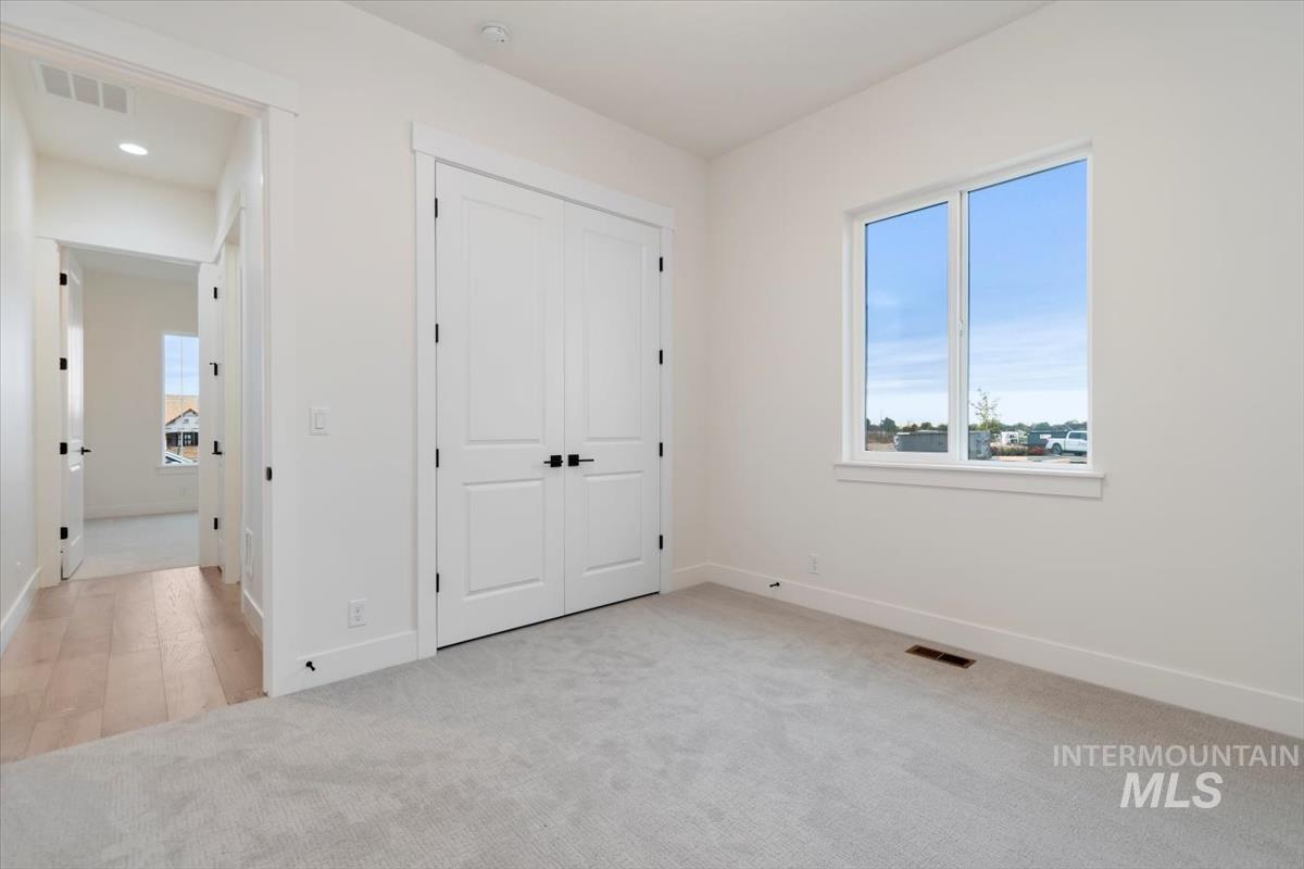 Unfurnished bedroom with light colored carpet and a closet