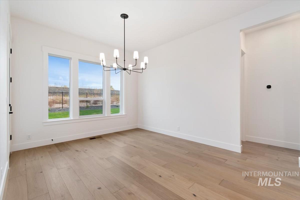 Empty room with light wood-style floors and a chandelier