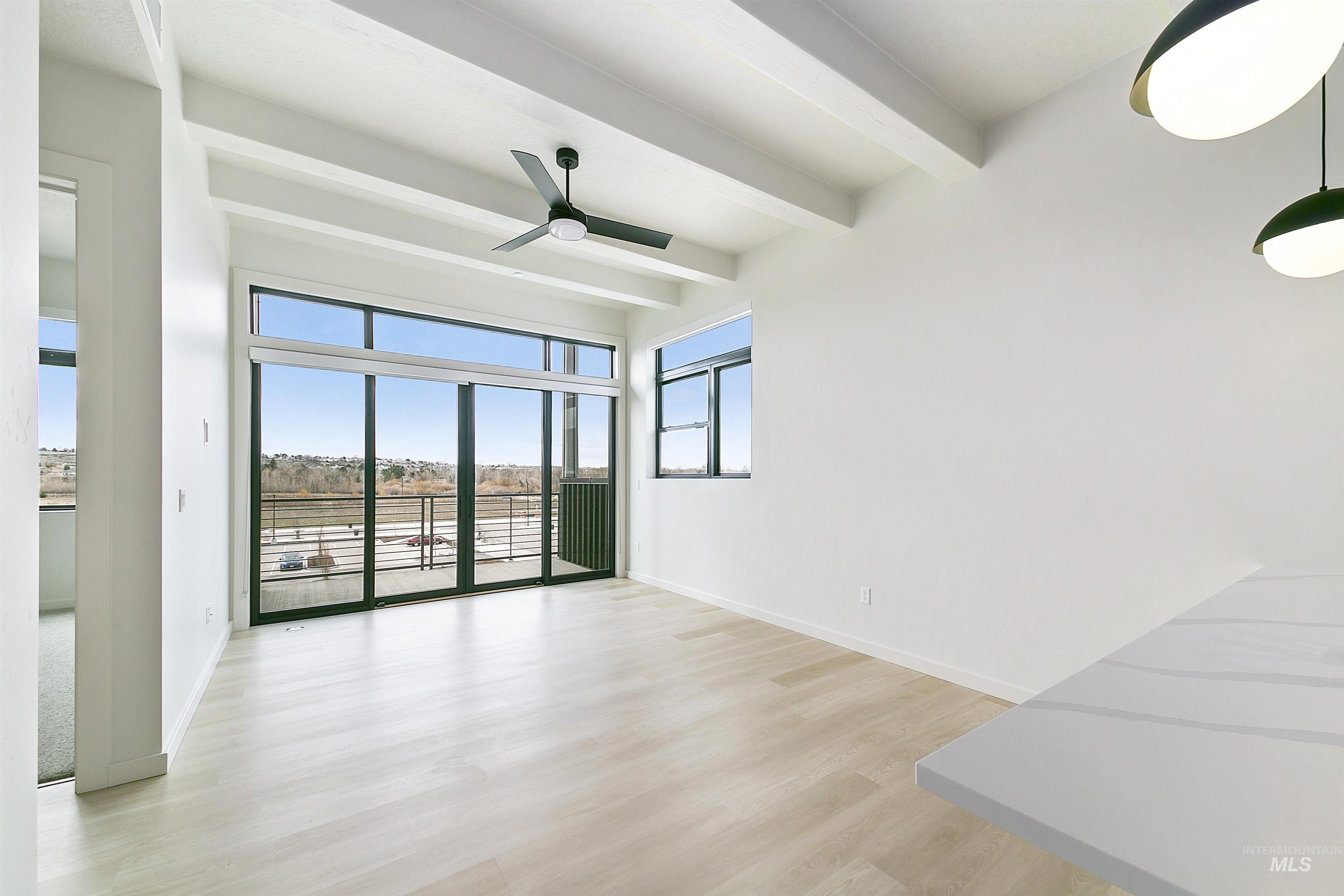 Spare room featuring beamed ceiling, ceiling fan, and light wood-style flooring